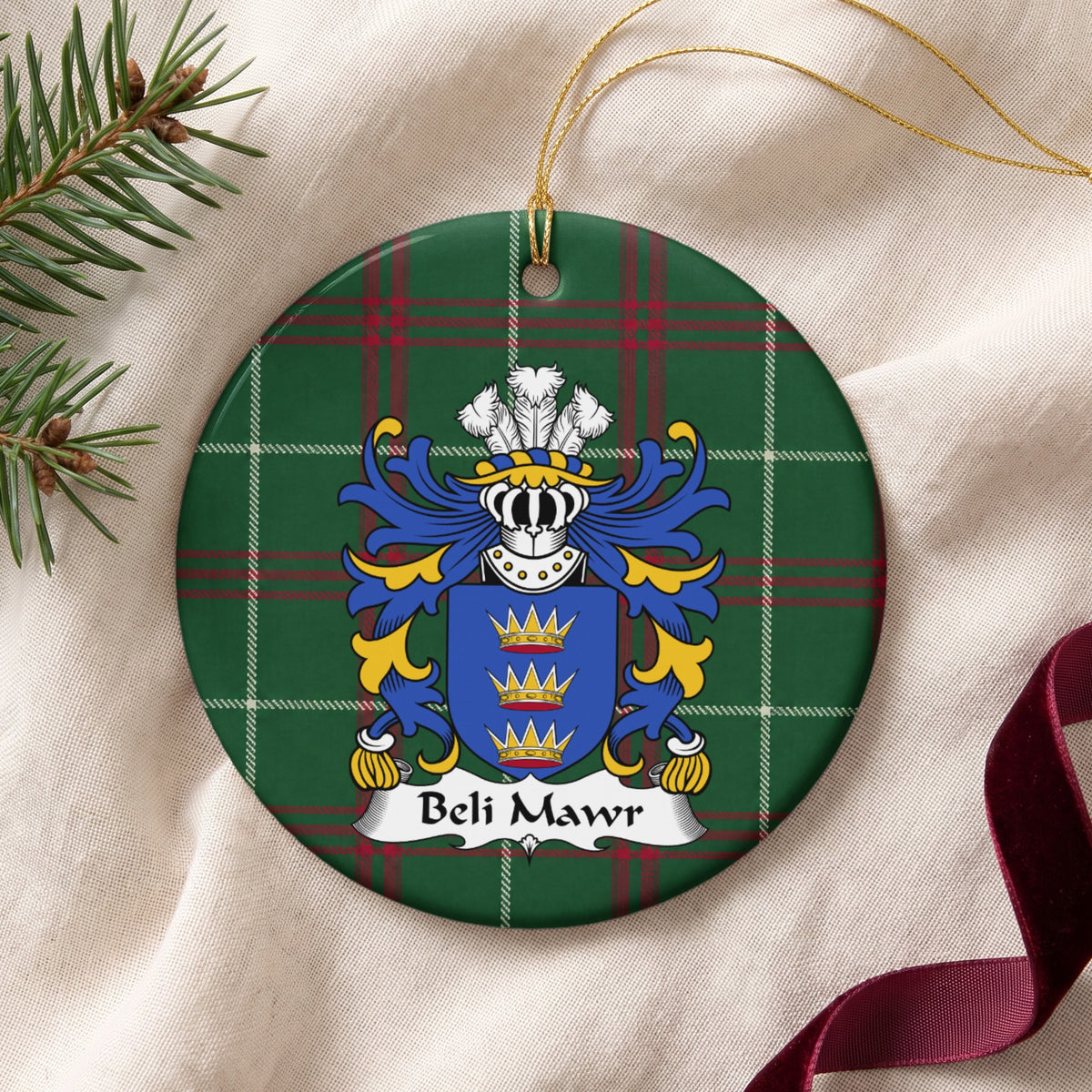 Beli Mawr ornament on cream fabric with gold string, evergreen and burgundy ribbon; three gold crowns on a blue shield on Welsh national tartan.
