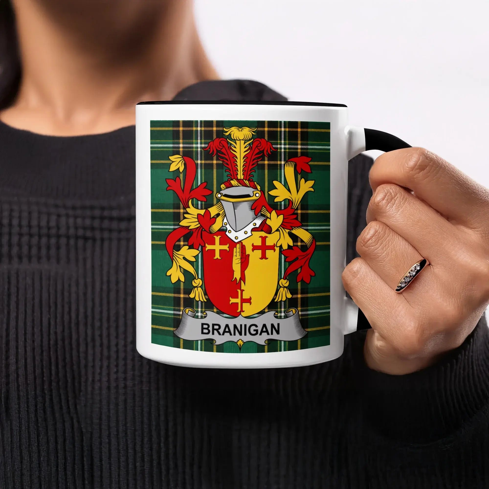 Branigan family crest on a black and white mug held by a person.