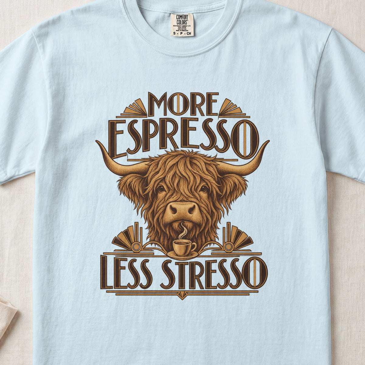 More Espresso, Less Stresso Highland cow design on a Chambray Comfort Colors 1717 T-shirt, flat lay