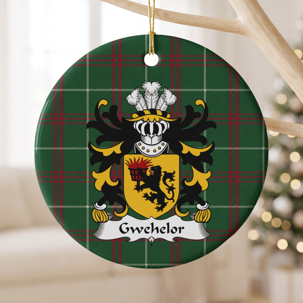 Gwehelor ornament hanging from a pale wooden branch; a black lion holding a flaming basket on a gold shield on Welsh national tartan.