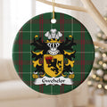 Gwehelor ornament hanging from a pale wooden branch; a black lion holding a flaming basket on a gold shield on Welsh national tartan.
