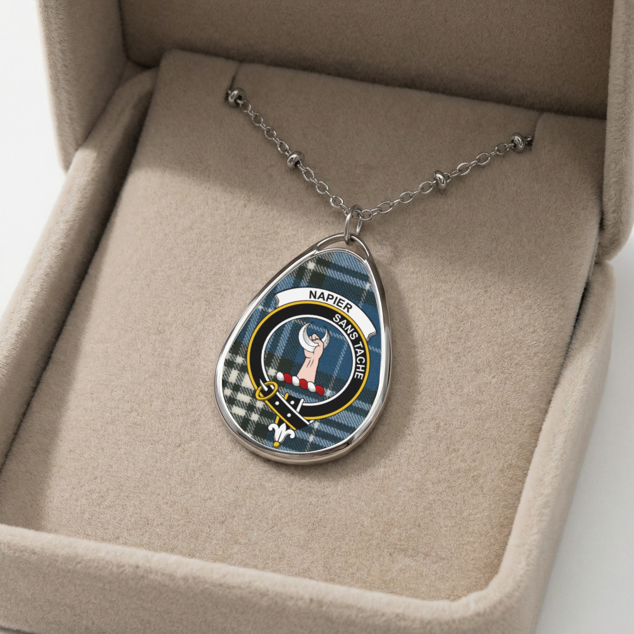 Oval pendant necklace with Napier clan crest on tartan, displayed in a jewelry box.