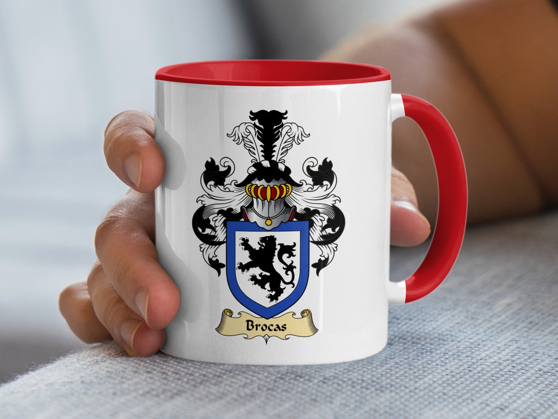 White mug with red handle featuring a blue and black coat of arms with a lion and the text "Brocas".