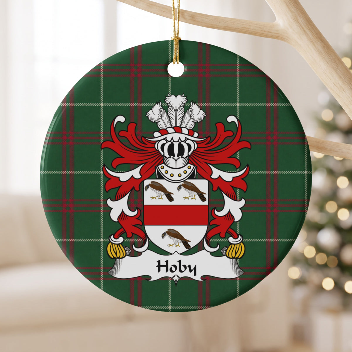 Hoby ornament hanging from a pale wooden branch; three brown birds and a red horizontal band on a white shield on Welsh national tartan.