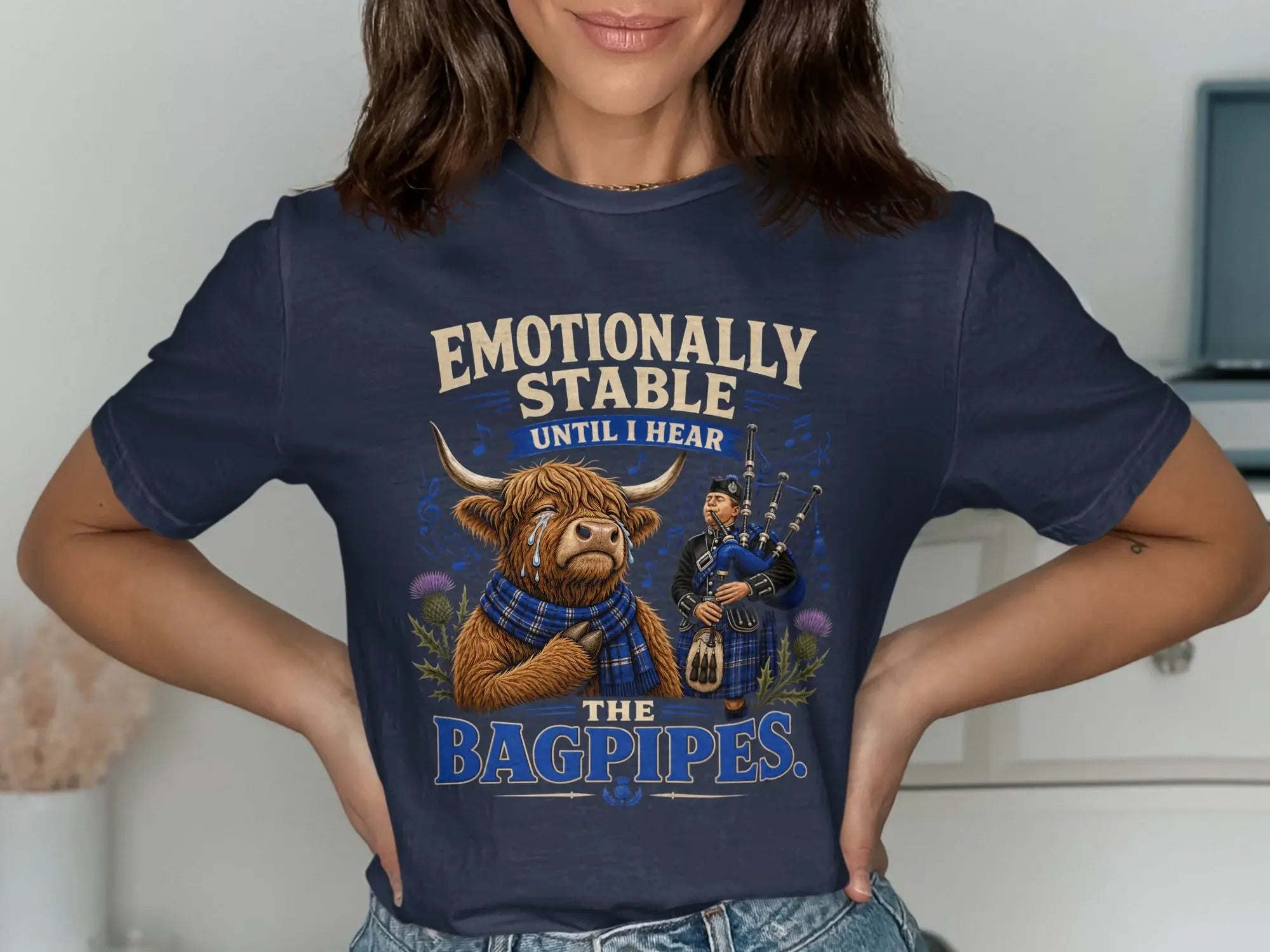 T-shirt with a Highland cow and bagpiper, text reads "Emotionally stable until I hear the bagpipes."