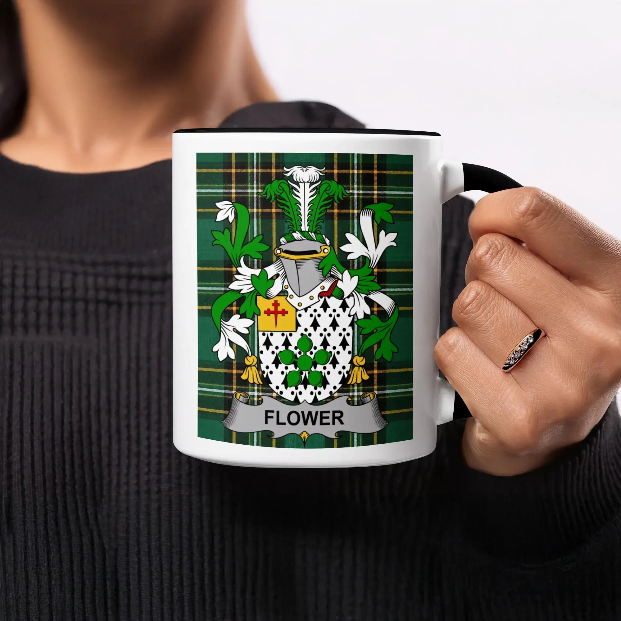 White mug with a black rim displaying a coat of arms on green plaid.