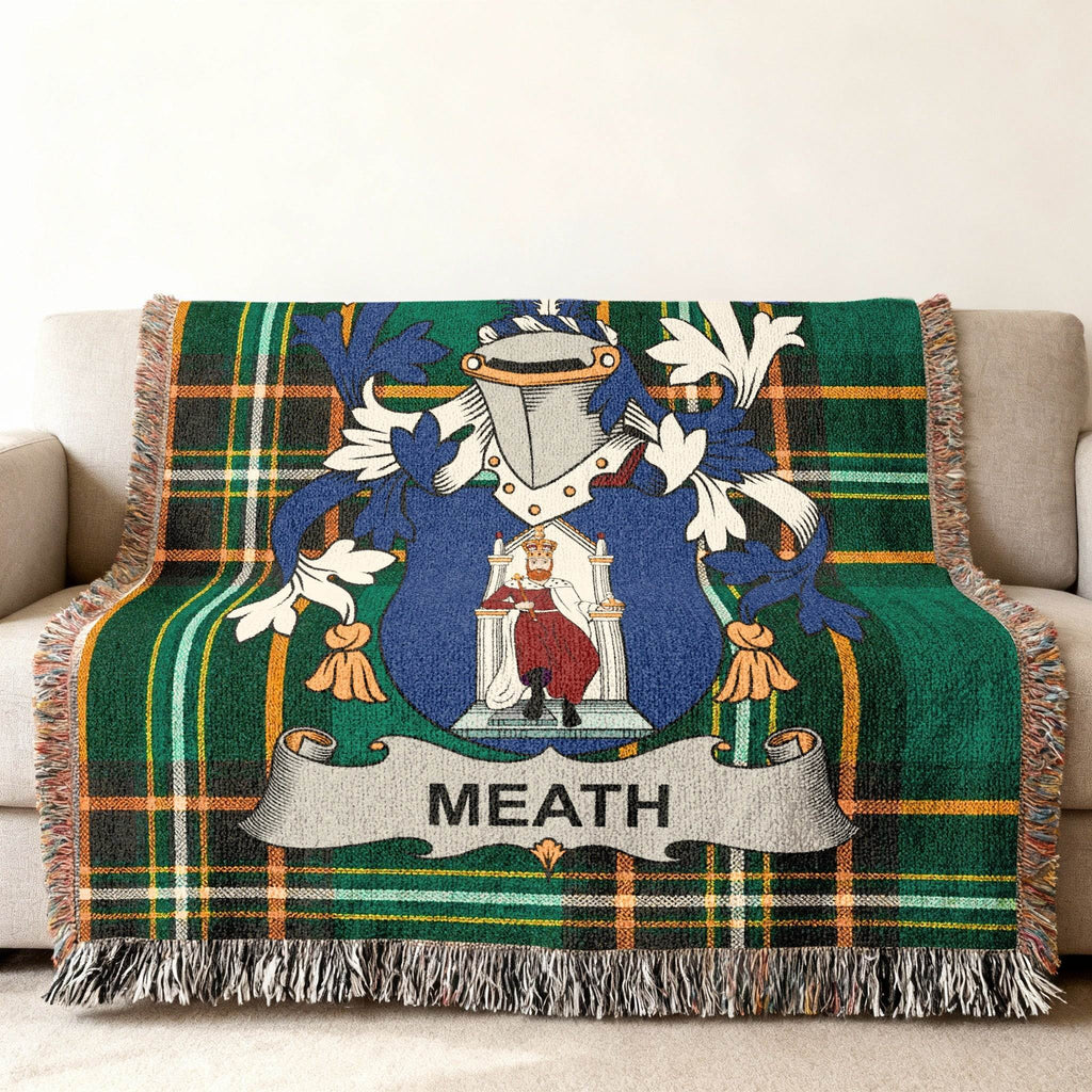 Woven throw blanket with Meath family crest over a green plaid pattern.