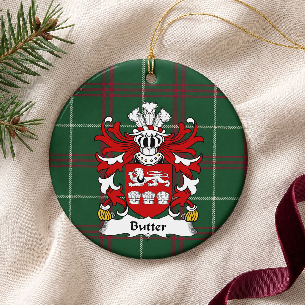 Butter ornament on cream fabric with gold string, evergreen and burgundy ribbon; a white lion above three white wheat sheaves on a red shield, with a black crescent on the lion on Welsh national tartan.