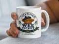 Mug with "Certified Wee Ticket" logo and Scottish Highland cow graphic.