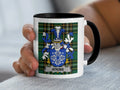 White mug with black handle featuring Atkins family crest on tartan background.
