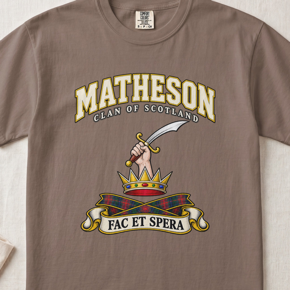Matheson Scottish clan T-shirt in Espresso, front view with a hand holding a curved sword above a gold crown and motto banner.
