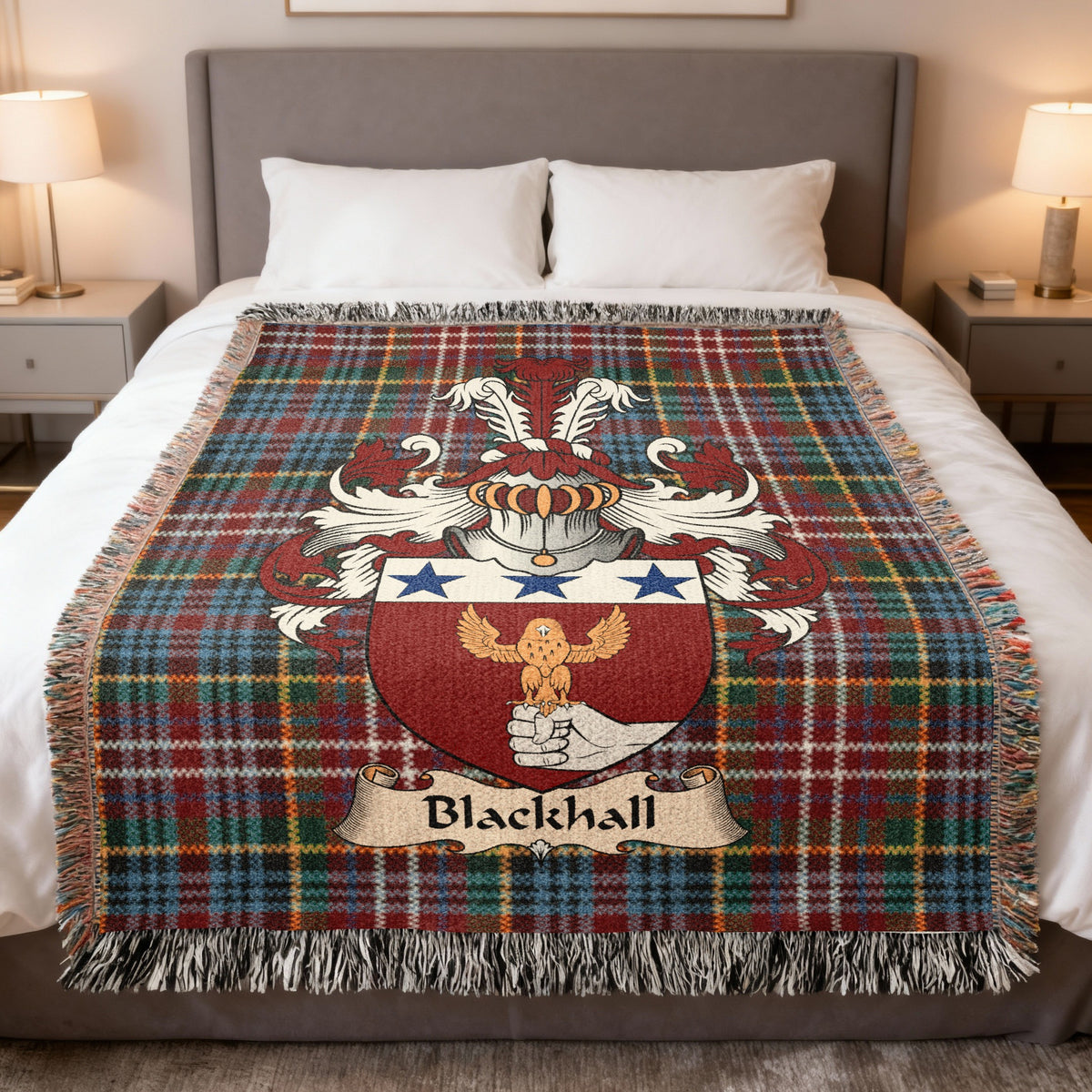 Blackhall Scottish family crest woven blanket on a Caledonia tartan background, displayed on a bed