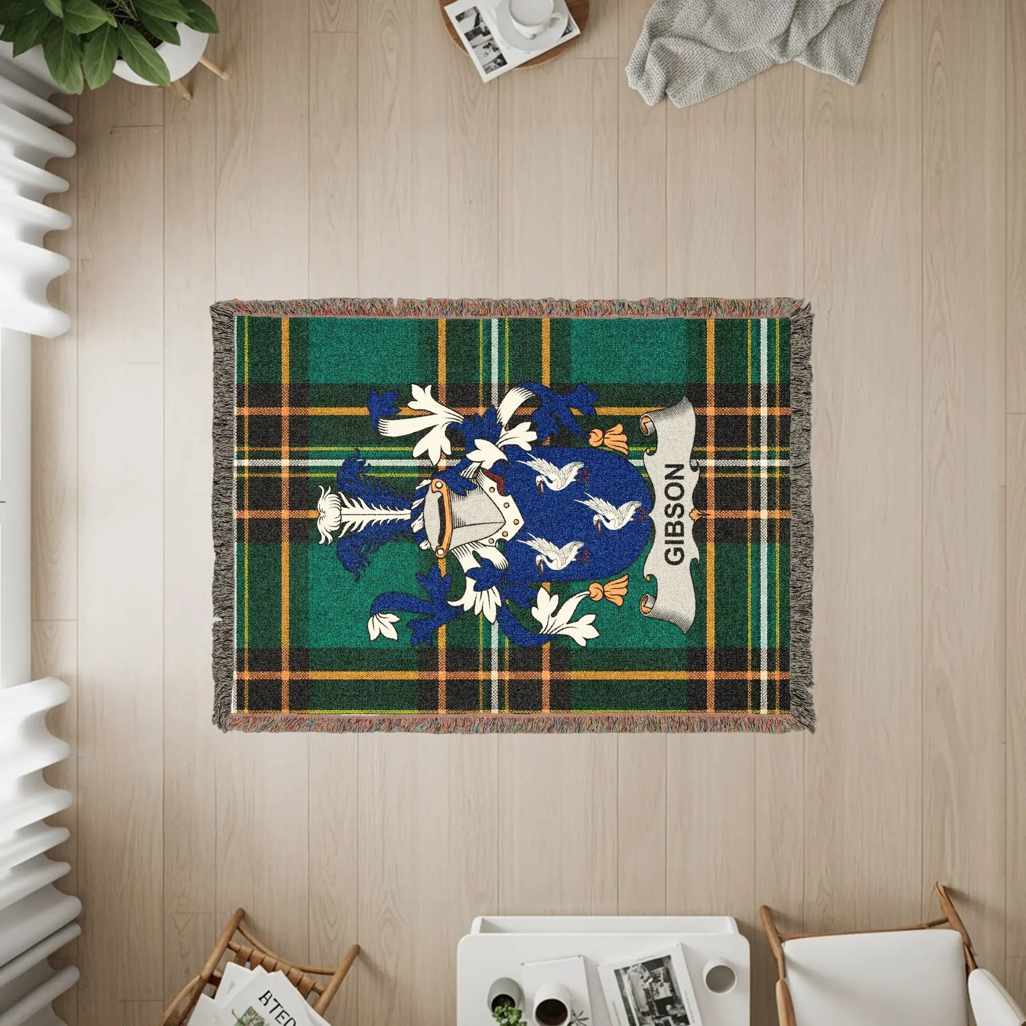 Woven throw blanket with a green plaid background and a coat of arms with the name "Gibson."