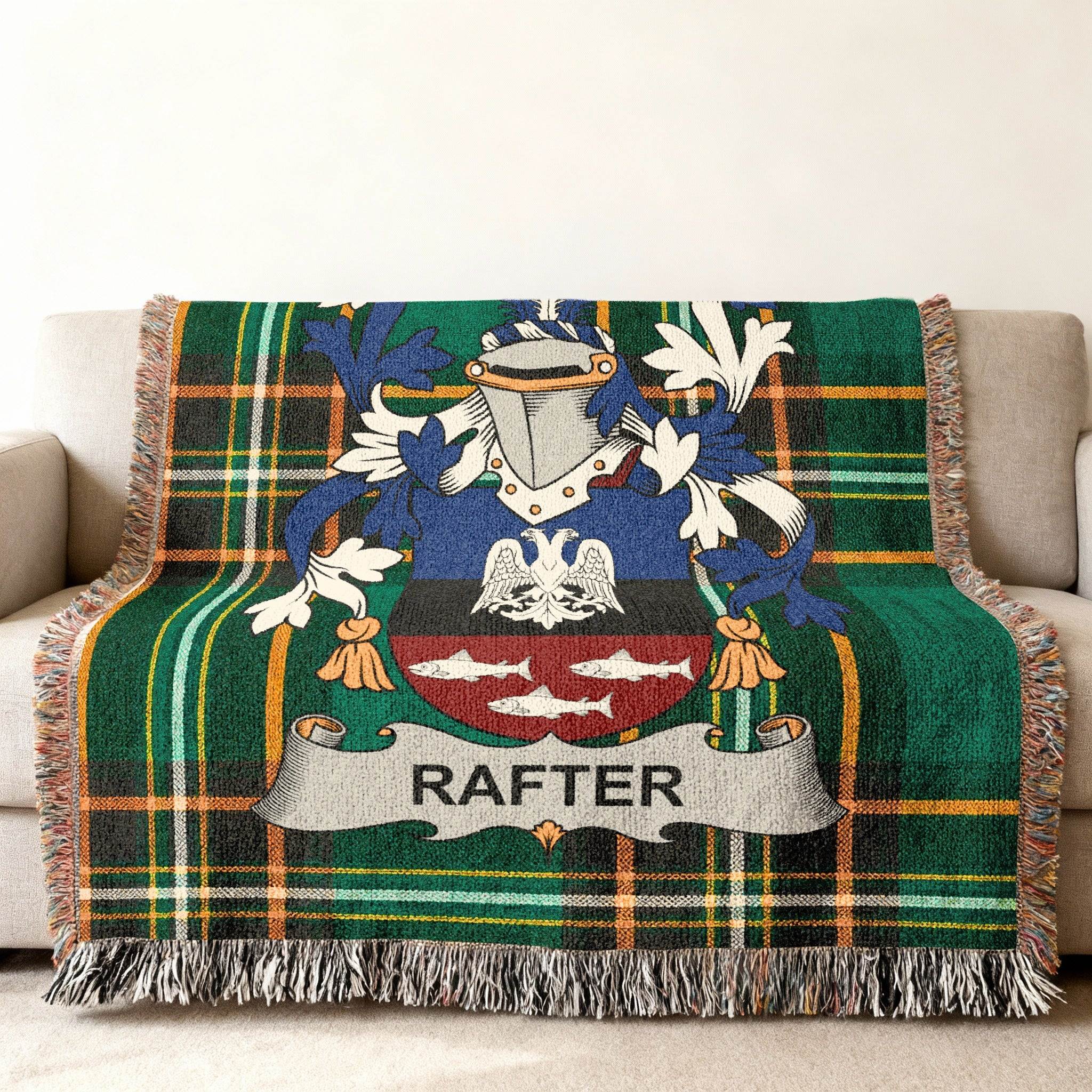 Green tartan blanket with Rafter family crest and fringe on a sofa.