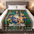 Plaid throw blanket with Orpen family crest on a bed.