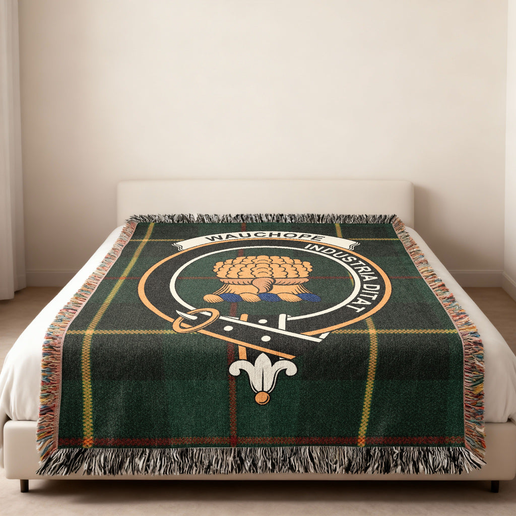 Wauchope Scottish woven blanket spread across a bed, showing the full crest design and tartan background