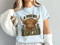Model wearing the A Wee Bit Highland Highland cow Comfort Colors T-shirt in Chambray