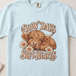 Slow Days, Soft Hearts Highland cow design on a Chambray Comfort Colors 1717 T-shirt, flat lay