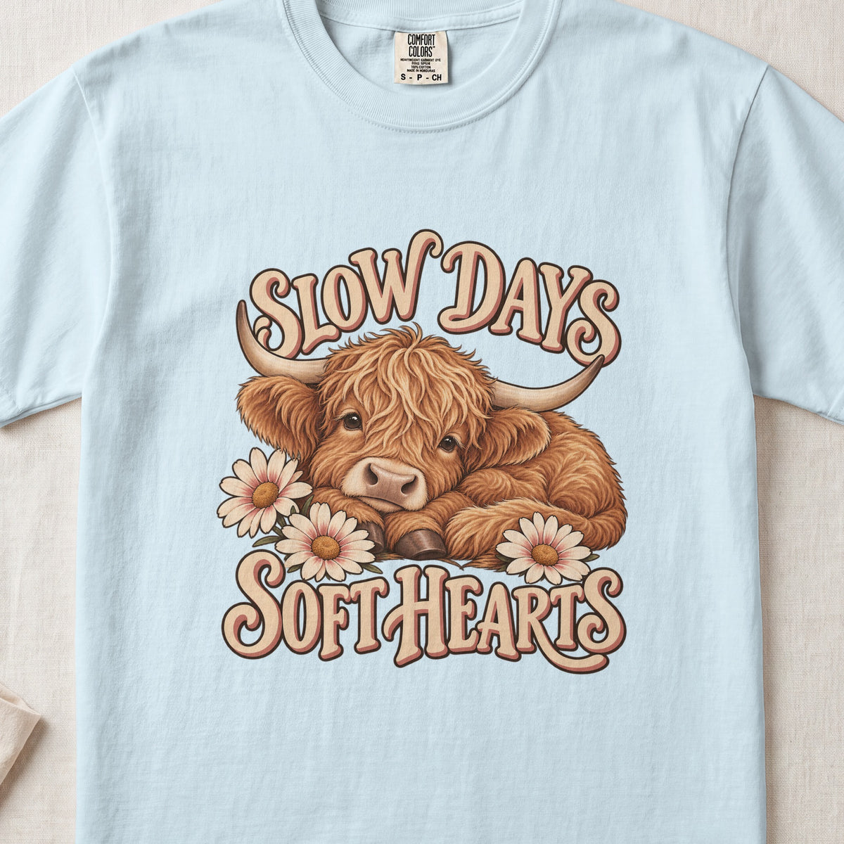 Slow Days, Soft Hearts Highland cow design on a Chambray Comfort Colors 1717 T-shirt, flat lay
