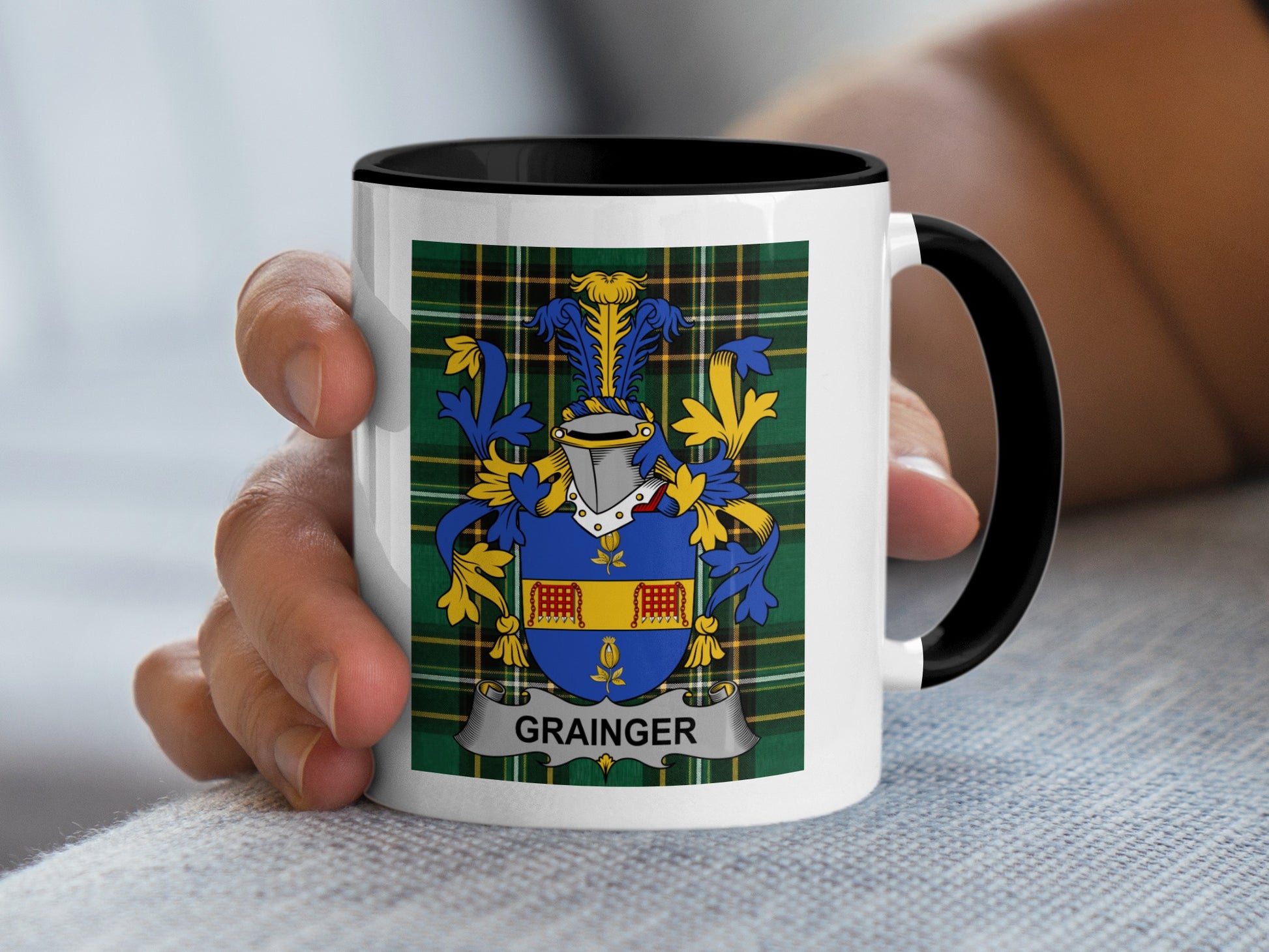 White mug with black rim featuring the Grainger family crest on a tartan background.