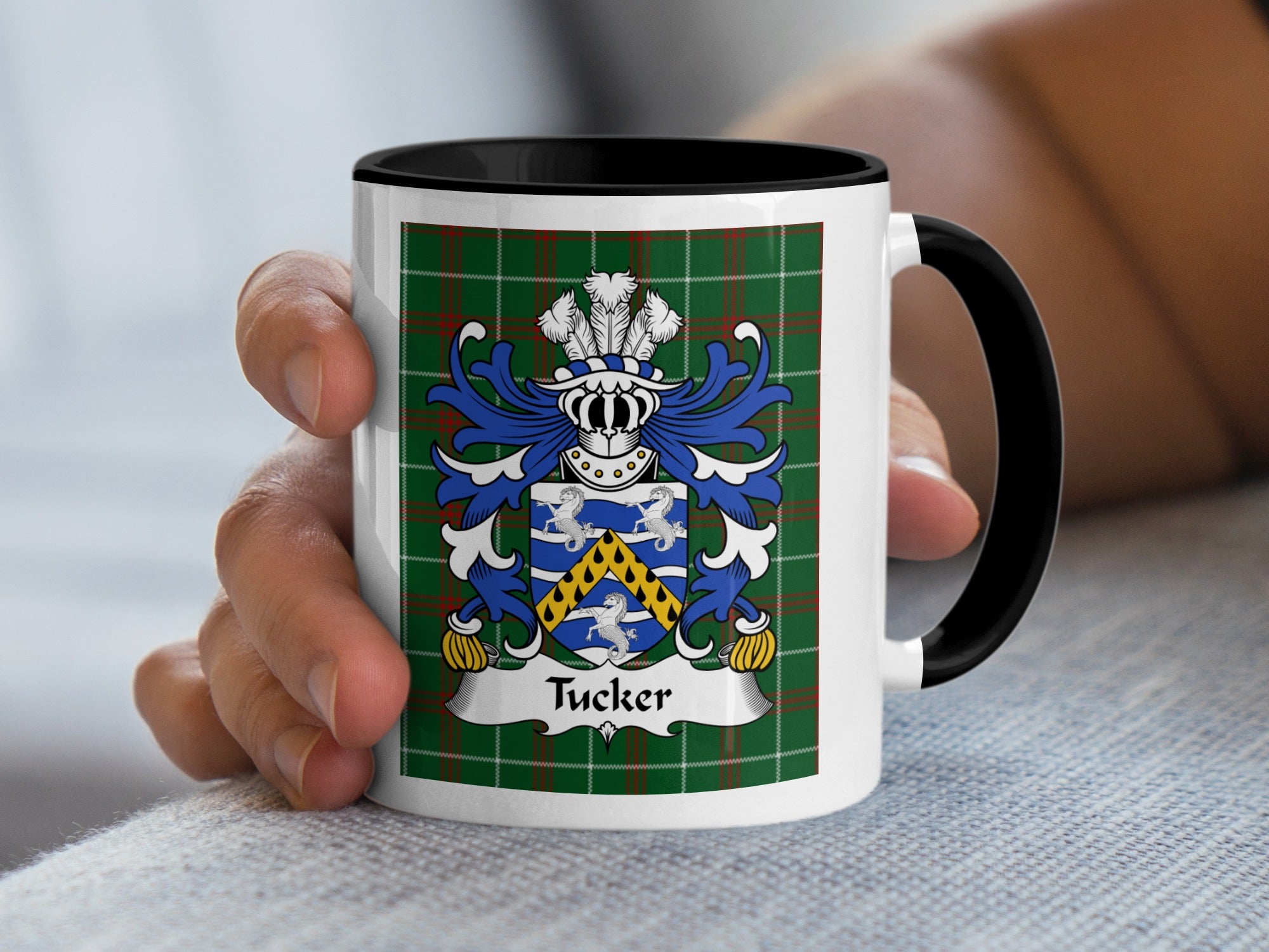 White mug with black handle featuring the Tucker family crest on a tartan background.