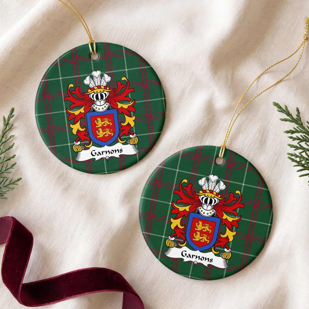 Two Garnons ornaments on cream fabric beside burgundy ribbon; two gold lions on a red shield enclosed by a blue border on Welsh national tartan.