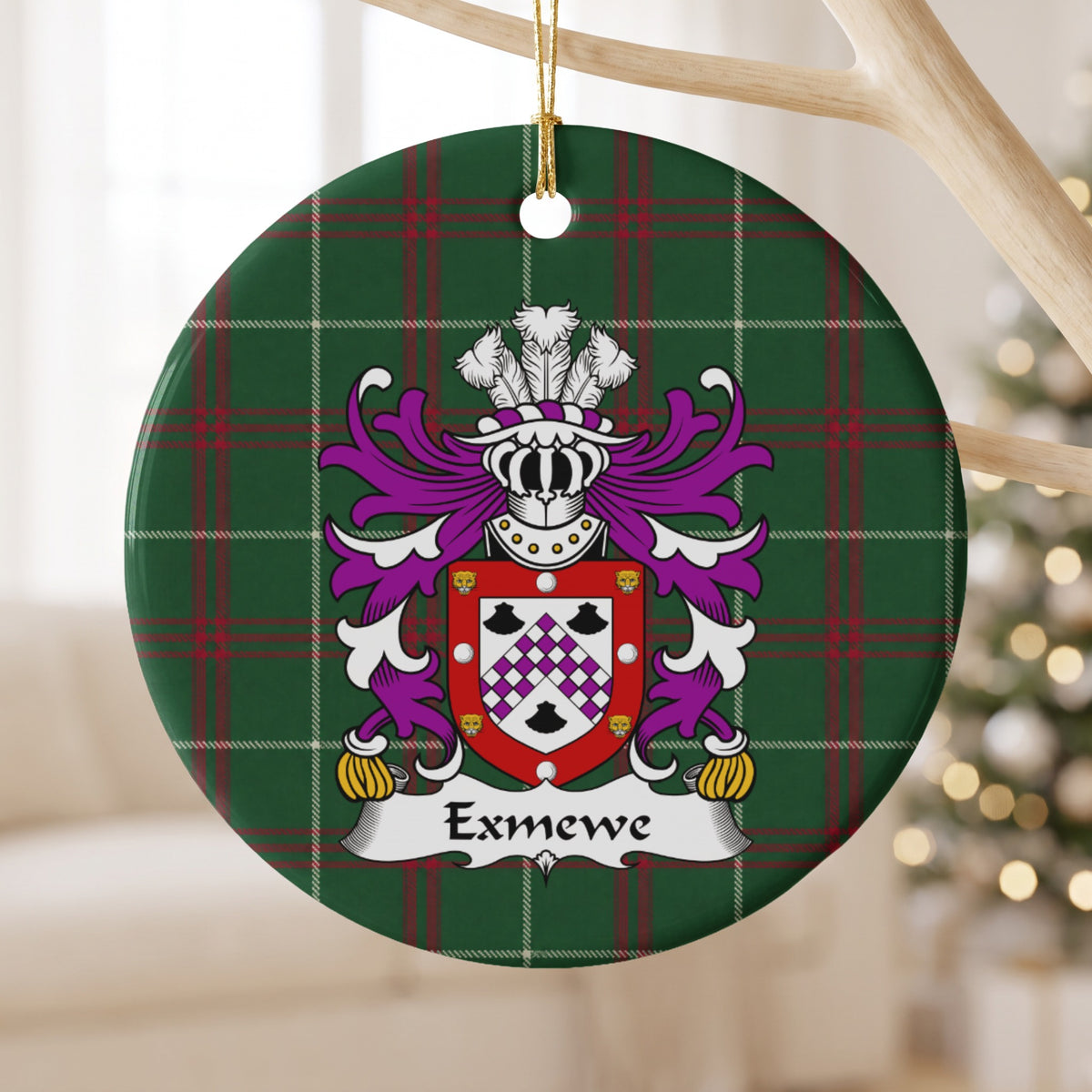 Exmewe ornament hanging from a pale wooden branch; a purple-and-white checked chevron between three black shells, within a red border decorated with white circles and gold animal faces on Welsh national tartan.