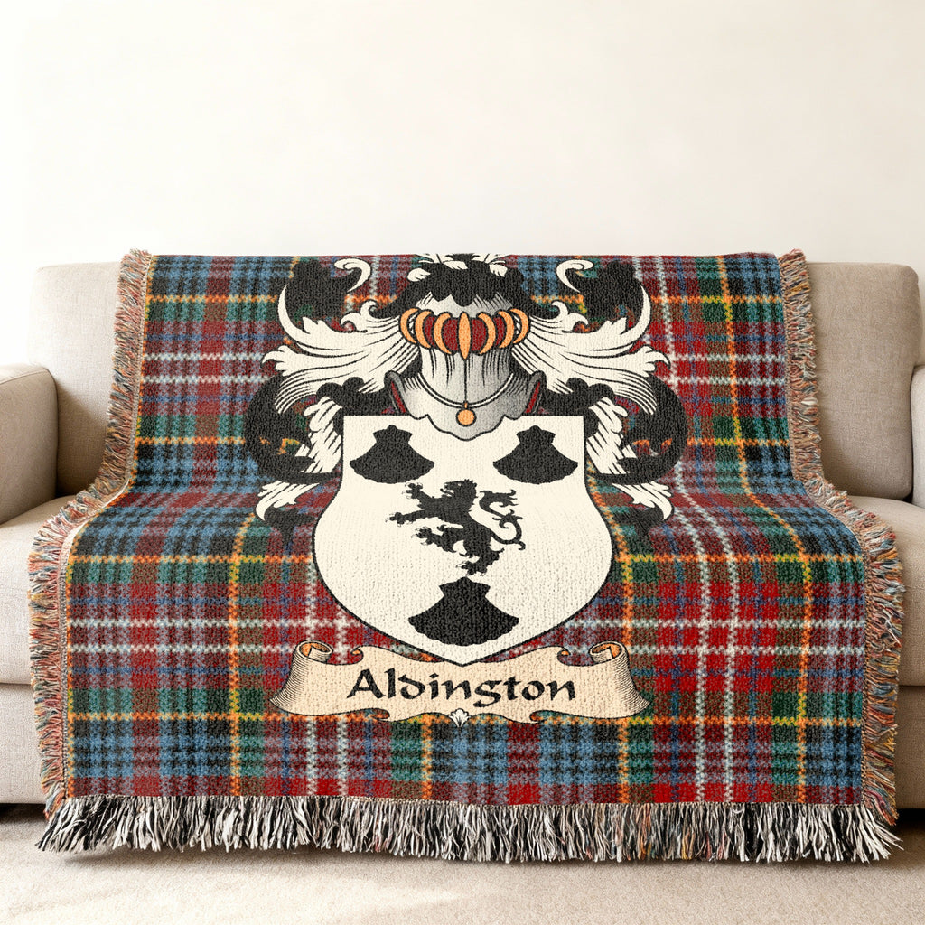 Alsington Scottish family shield woven blanket with Caledonia tartan background on a sofa