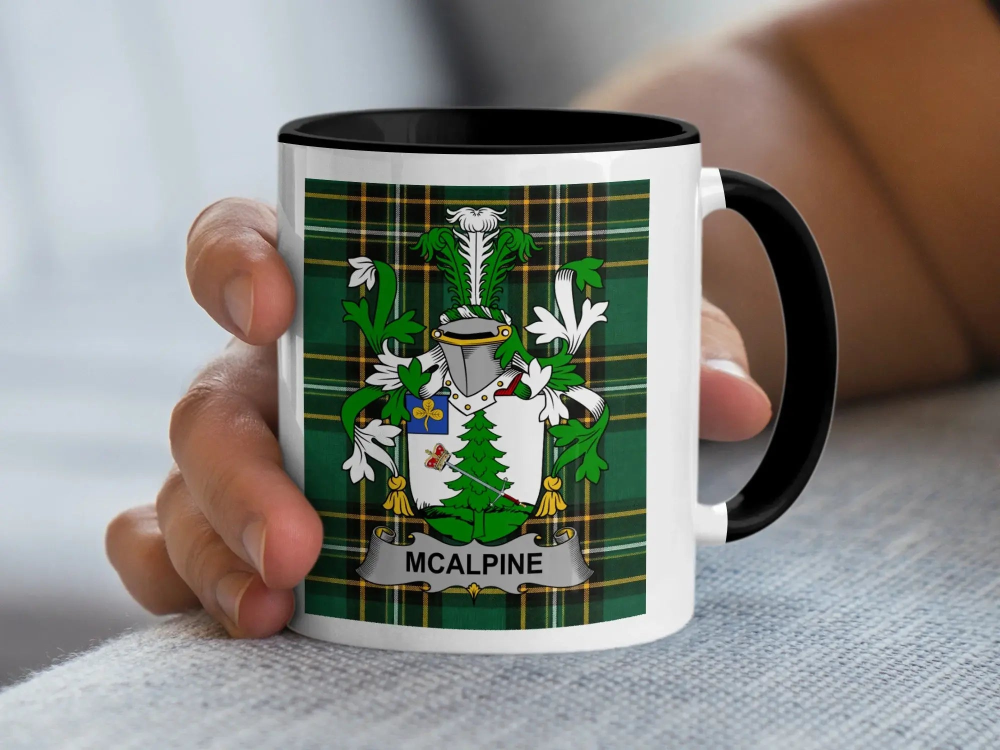 White mug with black rim featuring the McAlpin family crest on a green plaid background.