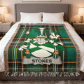 Tartan blanket with Stokes family crest displayed on a bed.
