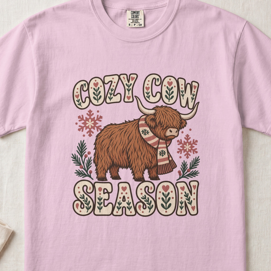 Cozy Cow Season Highland cow design on a Blossom Comfort Colors 1717 T-shirt, flat lay