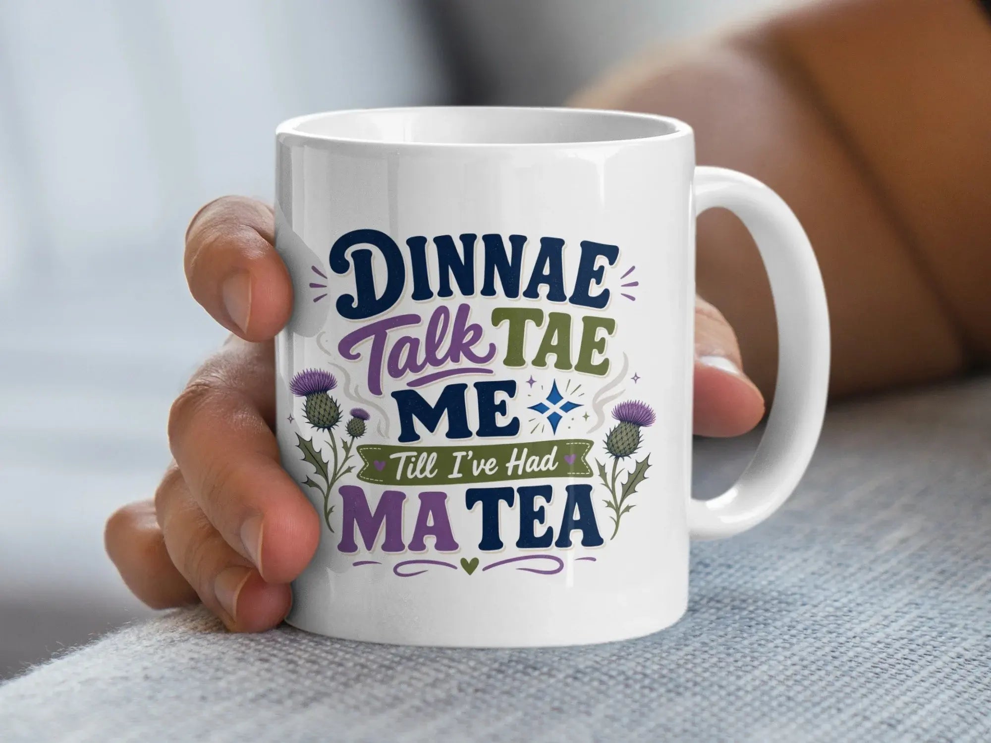 White mug with "Dinnae Talk Tae Me Till I've Had Ma Tea" text and thistles.