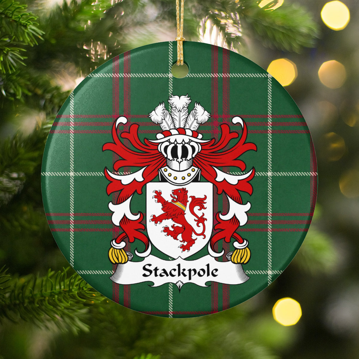 Stackpole family crest ornament with Welsh national tartan background, hanging by a gold cord among Christmas tree branches and warm lights.