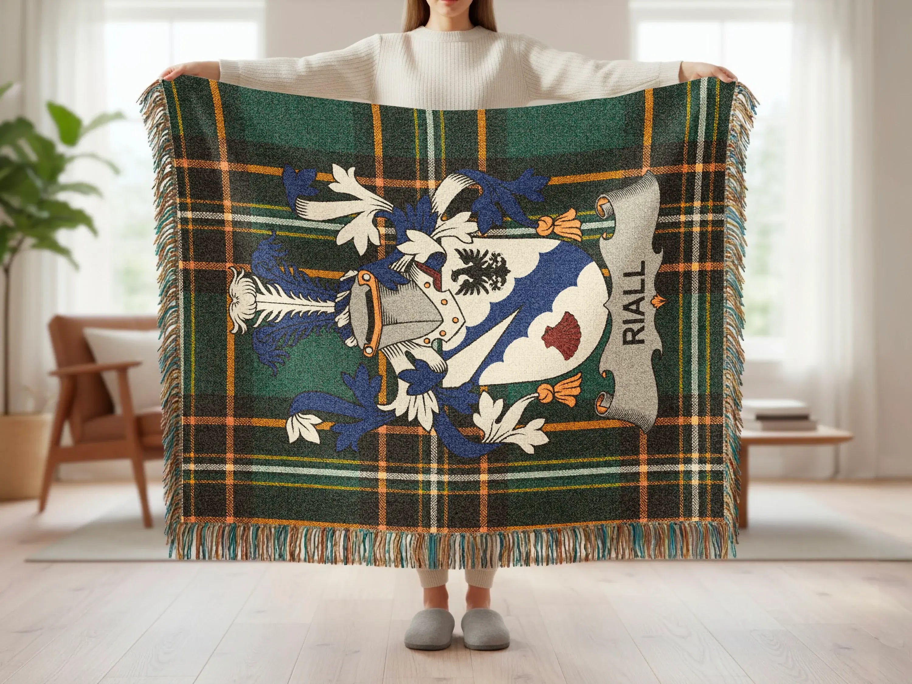 Tartan blanket with Riall crest and fringe, held by person.