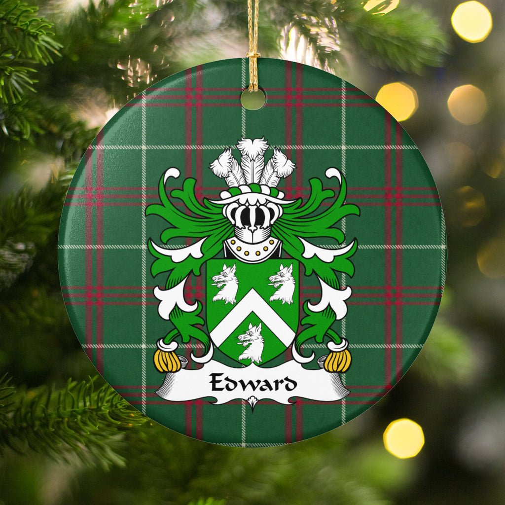 Edward Style 2 ornament hanging among Christmas tree branches and warm lights; a white chevron between three white wolf heads on a green shield on Welsh national tartan.