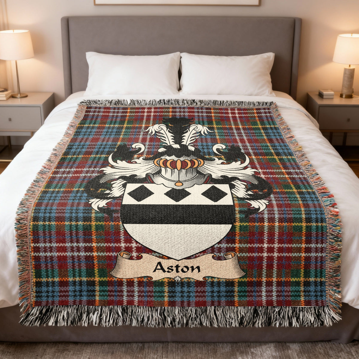 Aston Scottish family crest woven blanket on a Caledonia tartan background, displayed on a bed