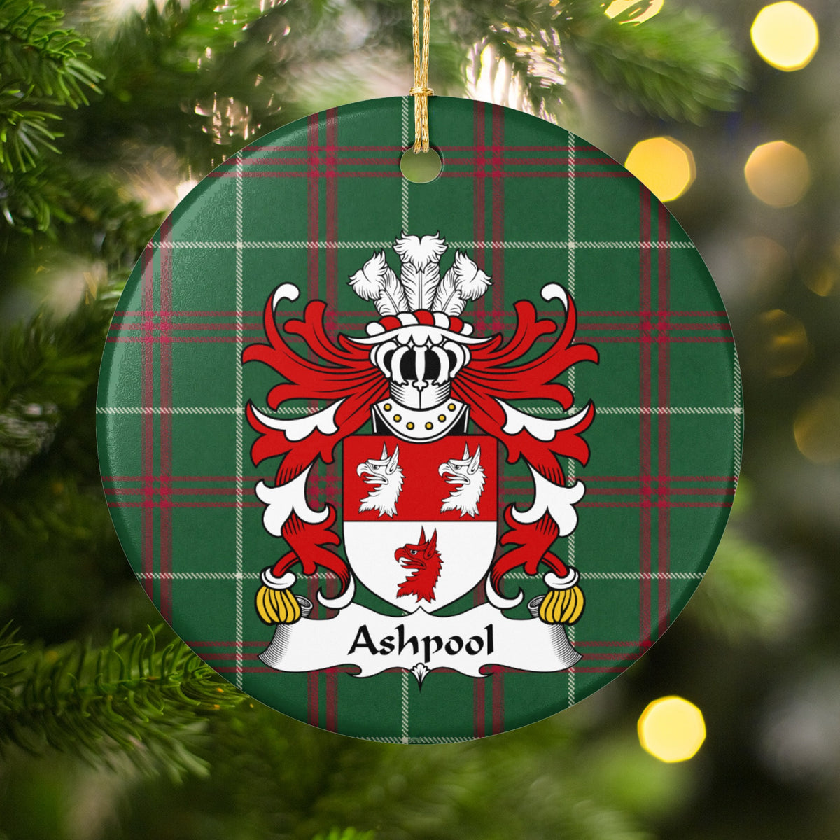 Ashpool ornament among Christmas tree branches and warm lights; two white wolf heads above one red wolf head on a red-and-white shield on Welsh national tartan.