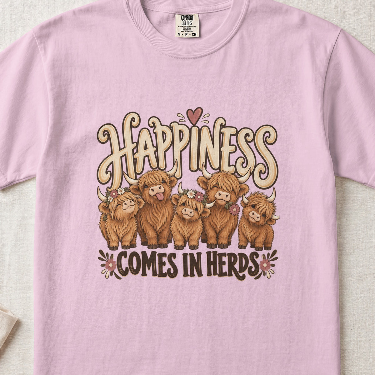 Happiness Comes in Herds Highland cow design on a Blossom Comfort Colors 1717 T-shirt, flat lay