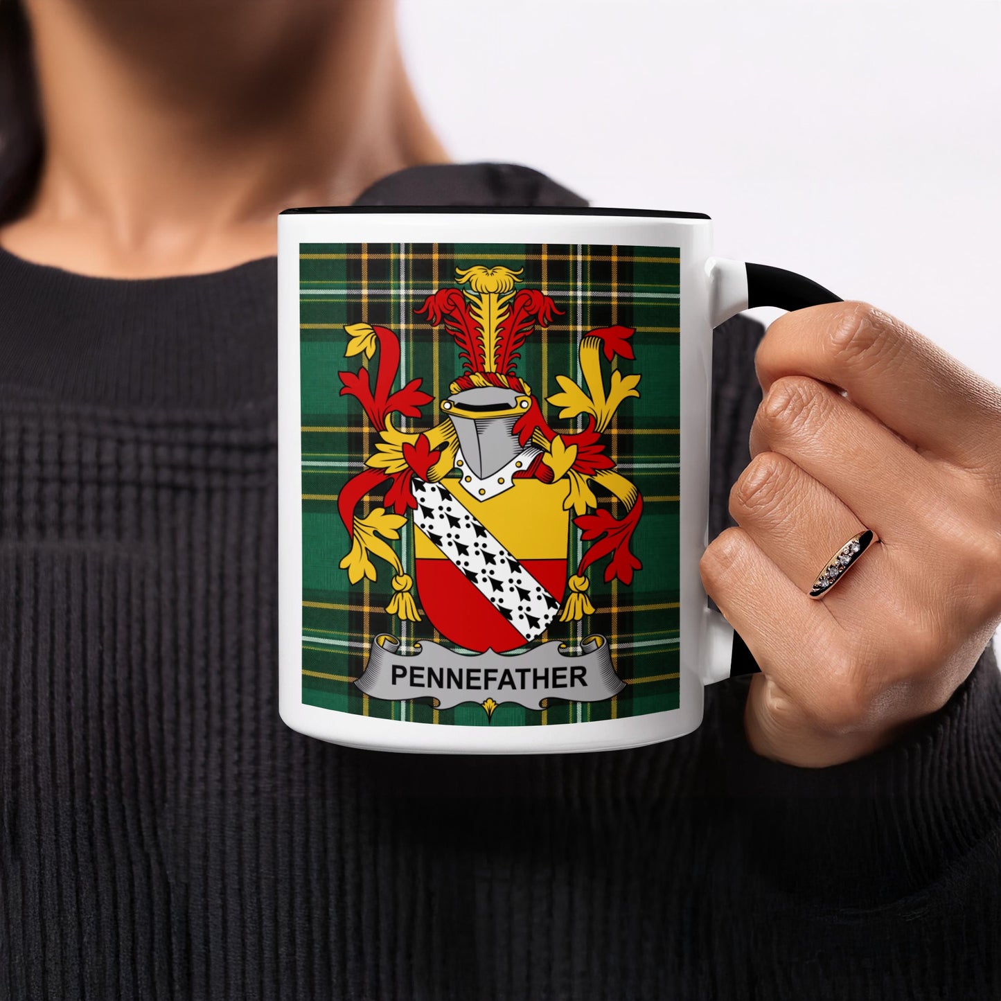 Mug with Pennefather family crest on tartan background, held by a person.
