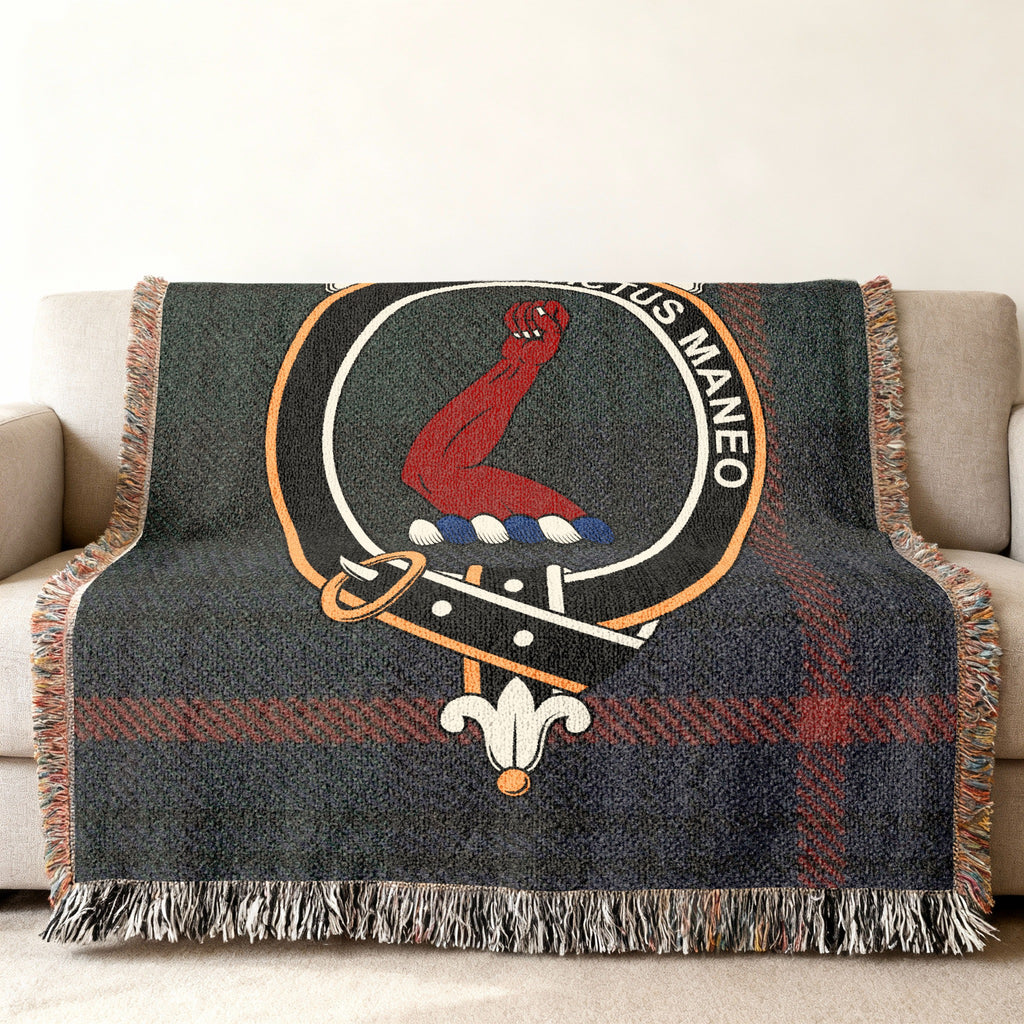 Close view of the Armstrong woven blanket draped over a sofa, showing the crest and fringed edges