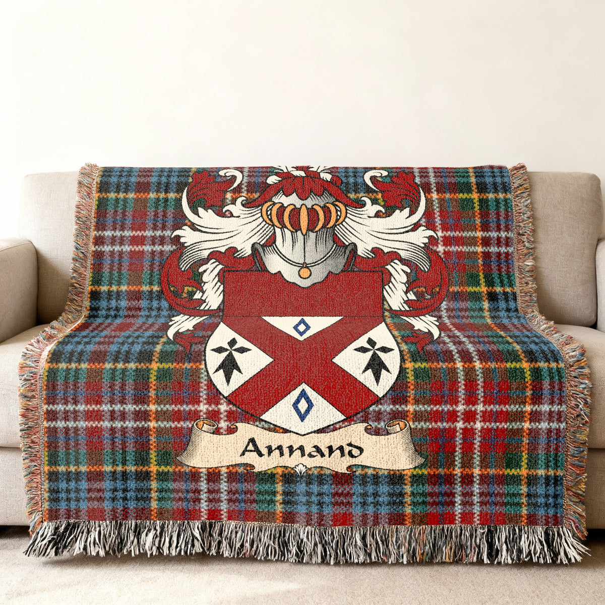 Annand Scottish family shield woven blanket with Caledonia tartan background on a sofa