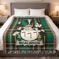 McAlindon tartan blanket with crest displayed on a bed.