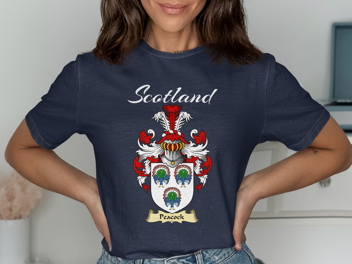 Model wearing a navy Peacock T-shirt featuring three colourful peacock motifs on a pale shield