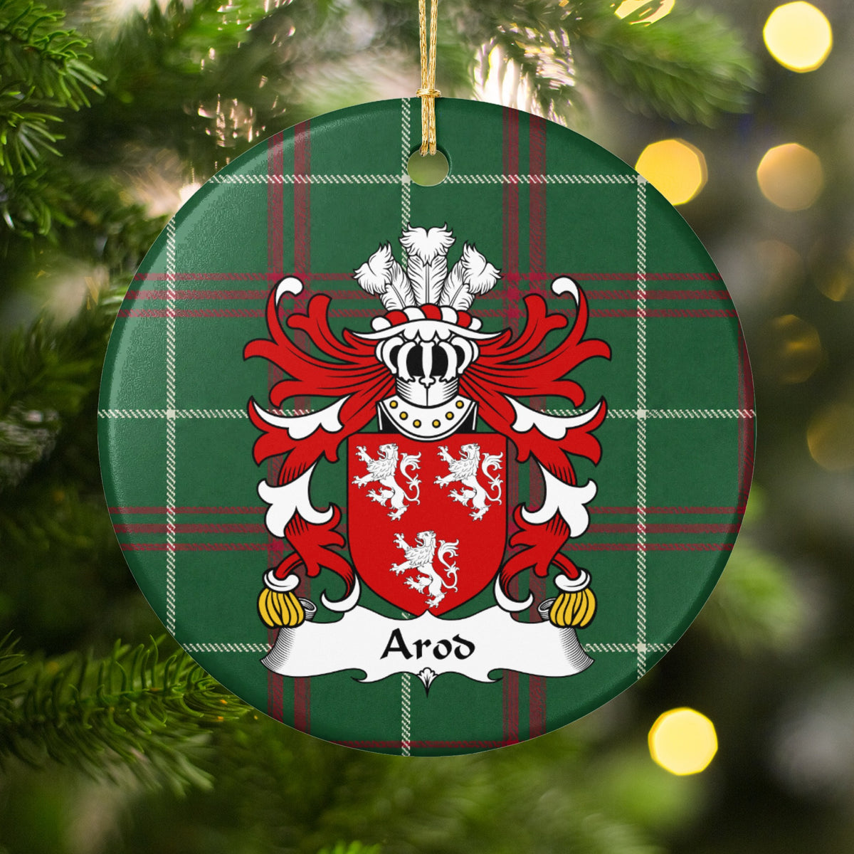 Arod family crest and surname on a round Welsh national tartan ornament, hanging by a gold cord among Christmas tree branches and warm golden lights.