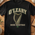 O'Leary Irish harp T-shirt in Black, with cream surname lettering, a gold-toned harp, green shamrock and “Irish Heritage” text.