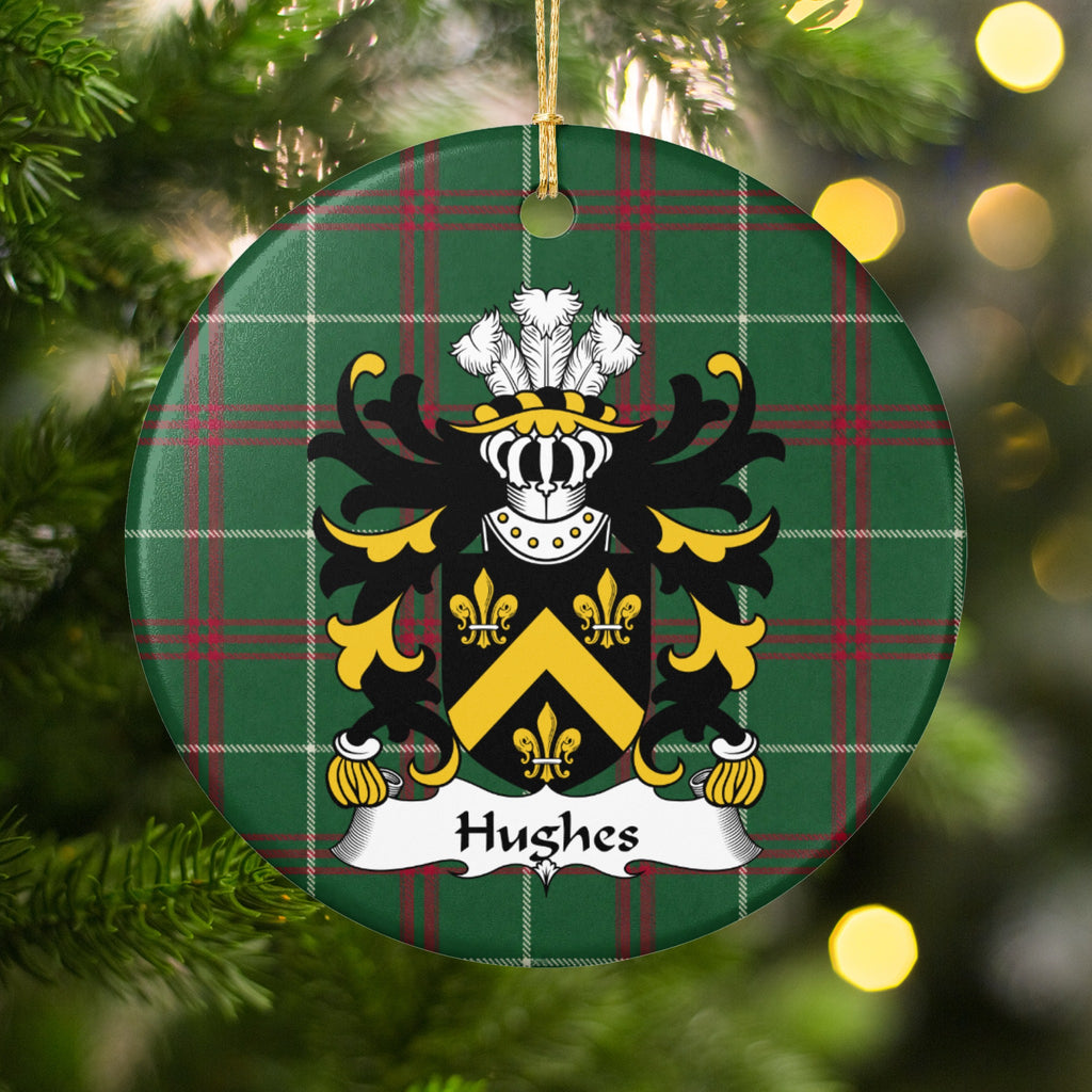 Hughes Style 1 ornament hanging among Christmas tree branches and warm lights; a gold chevron and three gold fleurs-de-lis on a black shield on Welsh national tartan.