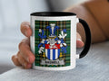 White mug with black rim featuring Bagwell family crest on plaid background.