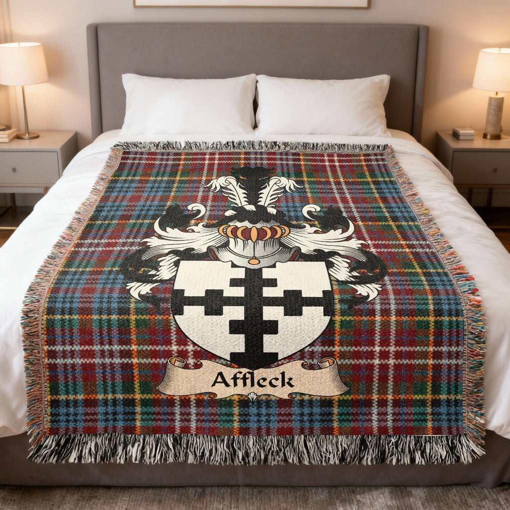 Affleck Scottish family crest woven blanket on a Caledonia tartan background, displayed on a bed