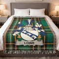 Green tartan blanket with Lowe family crest on a bed.