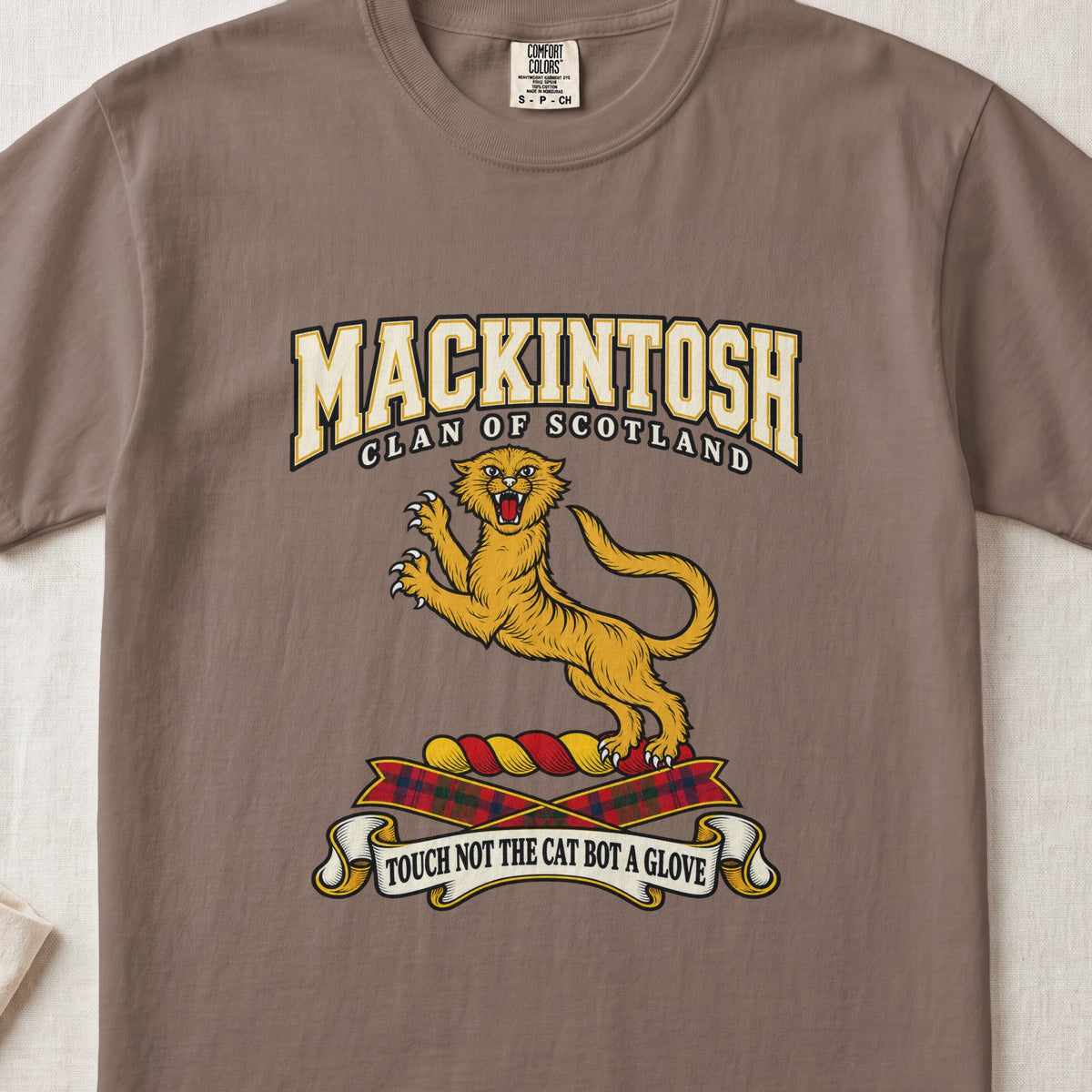 MacKintosh graphic T-shirt in Espresso brown, front flat lay showing varsity lettering and gold leaping wildcat with raised claws and open mouth.